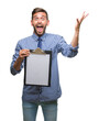 © Krakenimages.com - Young handsome business man holding clipboard over isolated background very happy and excited, winner expression celebrating victory screaming with big smile and raised hands