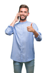 Canvas Print - Young handsome man speaking on the phone over isolated background happy with big smile doing ok sign, thumb up with fingers, excellent sign