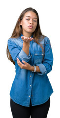 Poster - Young beautiful brunette woman wearing blue denim shirt over isolated background looking at the camera blowing a kiss with hand on air being lovely and sexy. Love expression.