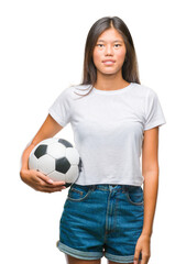 Wall Mural - Young asian woman holding football soccer ball over isolated background with a confident expression on smart face thinking serious