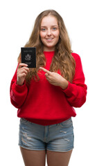 Sticker - Young blonde woman holding passport of United States of America very happy pointing with hand and finger