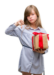 Sticker - Young blonde toddler holding a present with angry face, negative sign showing dislike with thumbs down, rejection concept