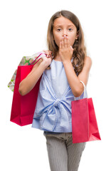 Poster - Brunette hispanic girl holding shopping bags cover mouth with hand shocked with shame for mistake, expression of fear, scared in silence, secret concept