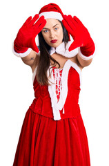 Poster - Young beautiful caucasian woman wearing santa claus costume doing frame using hands palms and fingers, camera perspective