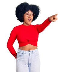 Canvas Print - Young african american girl wearing casual clothes and glasses pointing with finger surprised ahead, open mouth amazed expression, something on the front