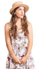 Wall Mural - Beautiful caucasian young woman wearing summer hat smiling looking to the side and staring away thinking.