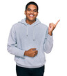 © Krakenimages.com - Young handsome hispanic man wearing casual sweatshirt with a big smile on face, pointing with hand and finger to the side looking at the camera.