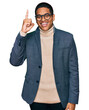 © Krakenimages.com - Young handsome hispanic man wearing business jacket and glasses pointing finger up with successful idea. exited and happy. number one.
