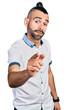 © Krakenimages.com - Hispanic man with ponytail wearing casual white shirt pointing displeased and frustrated to the camera, angry and furious with you