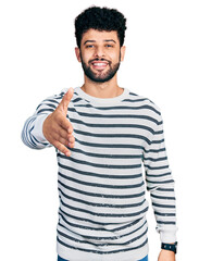 Poster - Young arab man with beard wearing casual striped sweater smiling friendly offering handshake as greeting and welcoming. successful business.