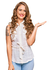 Wall Mural - Young blonde girl wearing casual clothes smiling cheerful presenting and pointing with palm of hand looking at the camera.