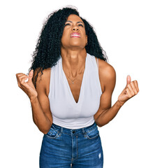 Wall Mural - Middle age african american woman wearing casual style with sleeveless shirt crazy and mad shouting and yelling with aggressive expression and arms raised. frustration concept.