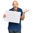 © Krakenimages.com - Middle age bald man holding blank empty banner celebrating victory with happy smile and winner expression with raised hands