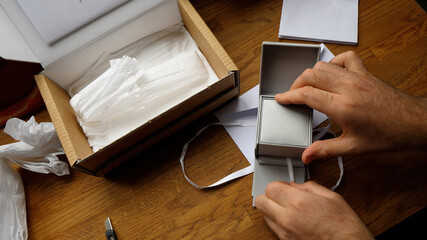 A man unboxing a fashion accessories gift for Valentine's Day, Roth holiday, Christmas, or birthday from a cardboard parcel, revealing a jewelry box inside with a silk bow, highlighting the excitement