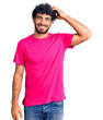 © Krakenimages.com - Handsome young man with curly hair and bear wearing casual pink tshirt confuse and wonder about question. uncertain with doubt, thinking with hand on head. pensive concept.