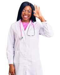 Canvas Print - Young african american woman wearing doctor stethoscope smiling positive doing ok sign with hand and fingers. successful expression.