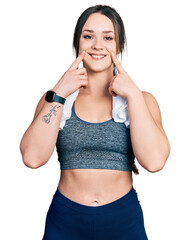 Wall Mural - Young hispanic girl wearing sportswear and towel smiling with open mouth, fingers pointing and forcing cheerful smile