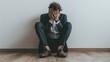 © BOONJUNG - Businessman facing emotional struggle, Depressed professional sitting on floor with hands covering face against white wall