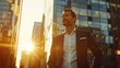 © Sirichat. Camphol - A successful, happy, wealthy businessman stands in a big city, a street, modern skyscrapers at sunset, thinking about his vision for the future.