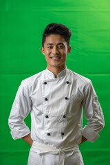 Wall Mural - A young chef smiling in front of a green background.