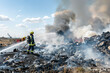 © Ekaterina Shvaygert - firefighters extinguish with hoses fire at the landfill with a lot os smoke