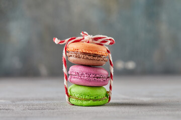 Wall Mural - Colorful macarons stacked and tied with rope on a concrete background