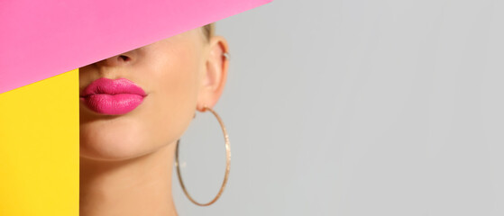 Wall Mural - Beautiful young woman with bright pink lipstick and color paper sheets on light background, closeup