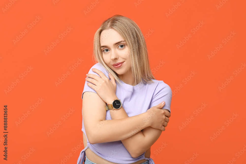 Young woman hugging herself on orange background