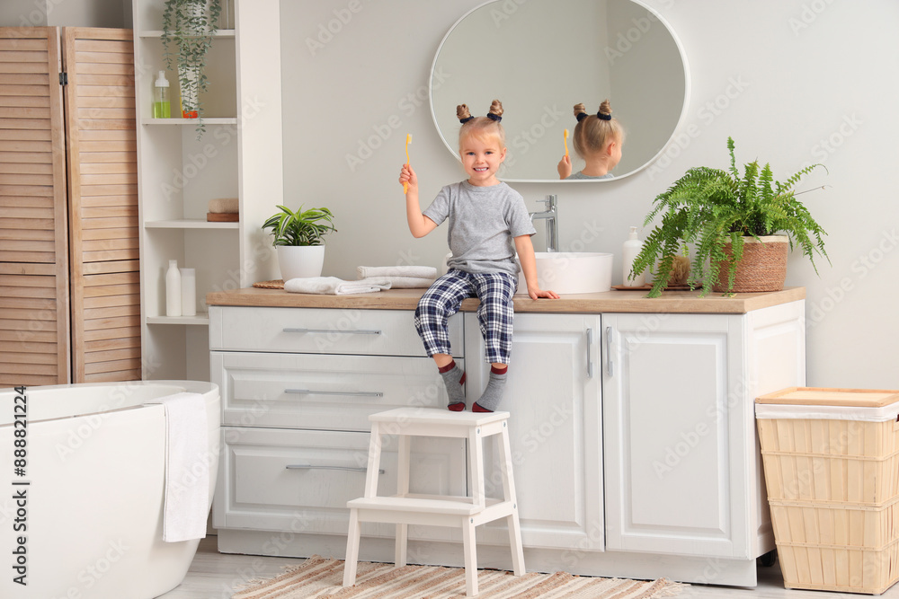 Cute little girl with toothbrush in bathroom