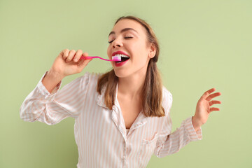 Wall Mural - Beautiful young woman brushing teeth on green background