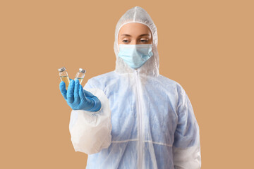 Canvas Print - Medical worker in protective suit and with ampules on beige background. Vaccination concept