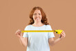 © Pixel-Shot - Young woman with measuring tape on beige background
