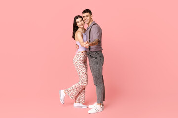 Wall Mural - Beautiful young couple dancing on pink background