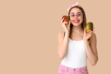 Poster - Beautiful young woman with sweet mango fruits on beige background