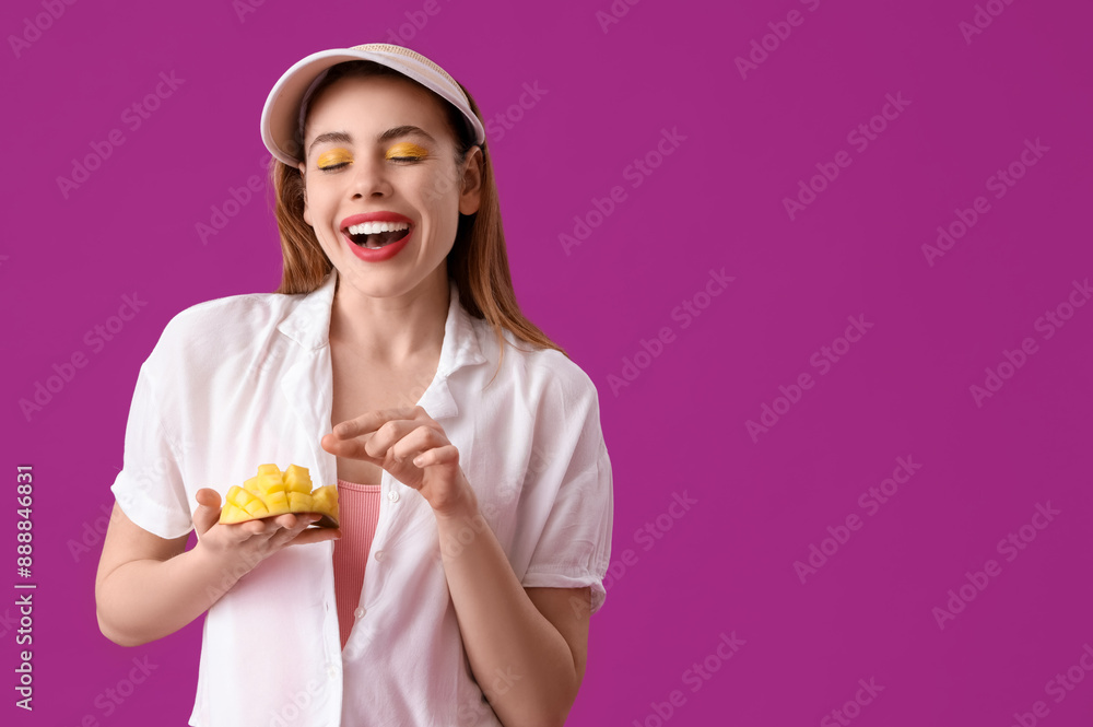 Happy young woman with cut sweet mango fruit on purple background