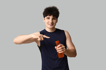 Poster - Sporty guy pointing at bottle of water on white background