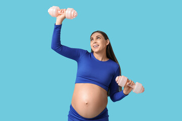 Wall Mural - Happy pregnant woman with dumbbells on color background