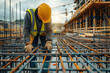 © visoot - A construction worker working on steel rebar frames at the site of an industrial building under creation, with the background the metal girder frame structure of a concrete modern commercial complex.