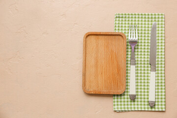 Wall Mural - Table setting with wooden board, cutlery and napkin on beige background