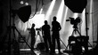 © Chatchanan - The silhouette of a film crew working behind bright studio lights, setting up for a high-end commercial shoot.