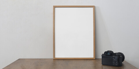 mock up. living room interior with wooden desk,  professional mirrorless photo camera. Mockup template white empty wood frame for picture.