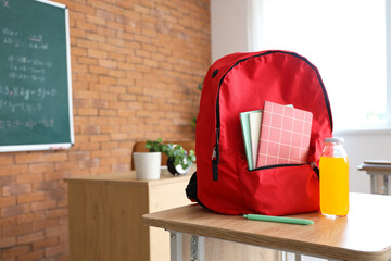 Wall Mural - Red backpack with copybooks and juice on desk in classroom