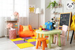 © Pixel-Shot - Interior of children's room with beanbag, toys and backpack on table