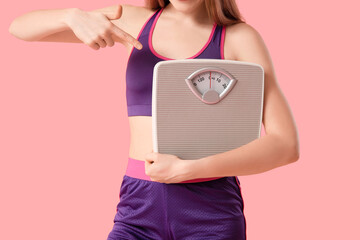 Poster - Sporty young woman with measuring scales on pink background, closeup. Diet concept