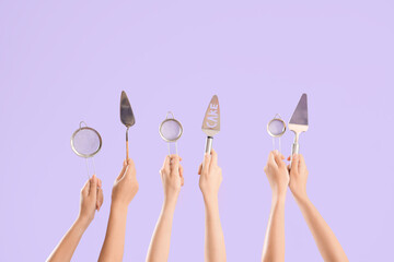 Wall Mural - Female hands with spatulas and sieves on purple background