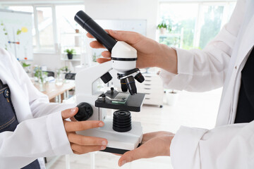 Poster - Teenage girl and teacher with microscope in Biology class, closeup