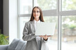© Pixel-Shot - Beautiful young happy businesswoman working with laptop near window in office