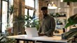 © Lala - A man with inclusivity stands at a standing desk in a modern office space working on a laptop
