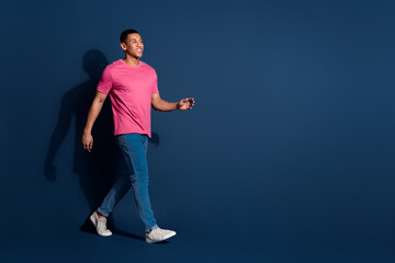 Sticker - Full body photo of young funny guy wearing casual pink t shirt and jeans strolling in his brand new outfit isolated on dark blue color background