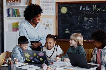 empathic female teacher smiling answering kids question while conducting lesson in primary school wi